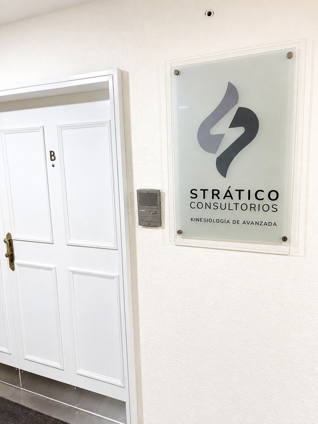 Cartel esmerilado de Strático Consultorios, kinesiología de avanzada, junto a la puerta B del piso 11